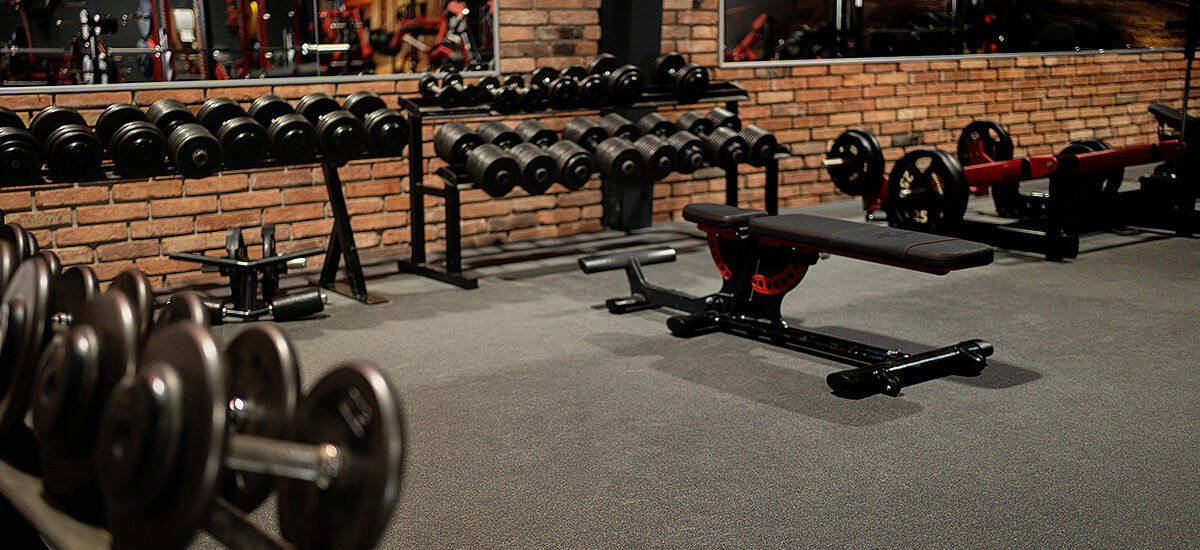 Dunkler Bodenbelag im Fitnessstudio mit verschiedenen Trainingsgeräten