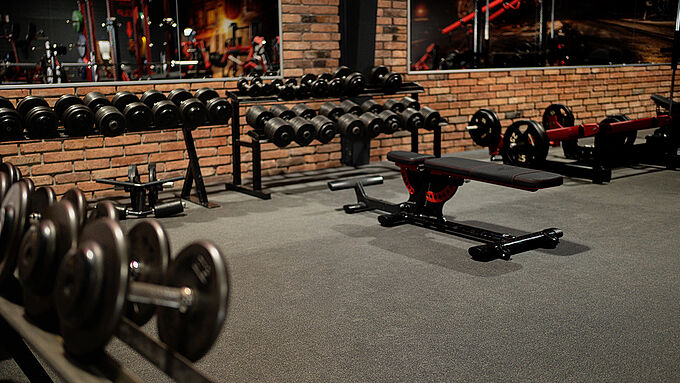 Dunkler Bodenbelag im Fitnessstudio mit verschiedenen Trainingsgeräten